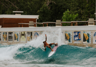 man standing on surfboard, catching a wave at waco surf