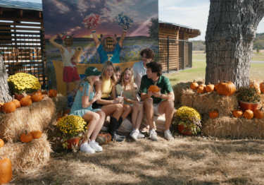friends sitting on haybales surrounded by pumpkins