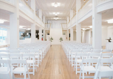 inside view of wedding venue, rows of white chairs with an aisle down the middle